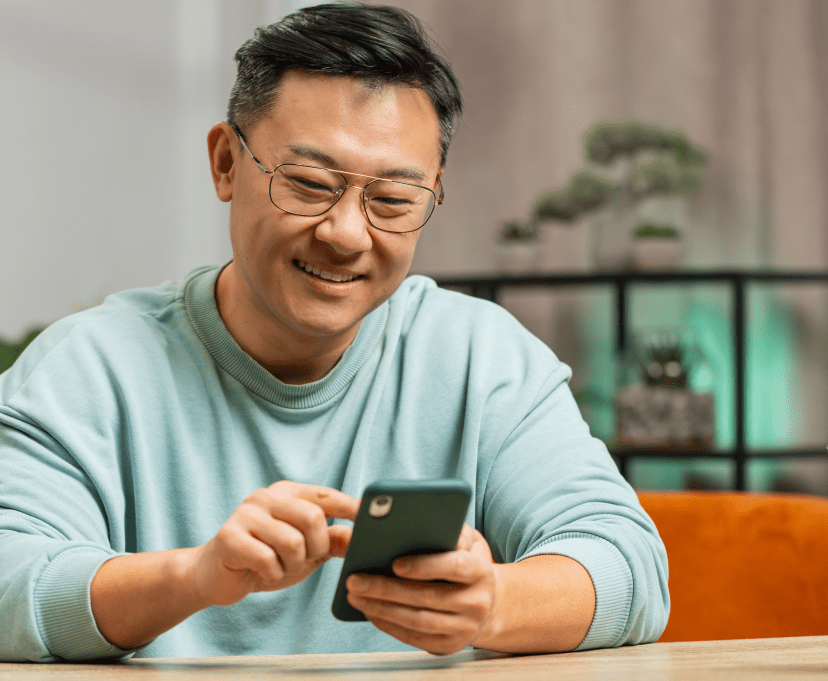 Man with dark hair and glasses scrolling mobile phone