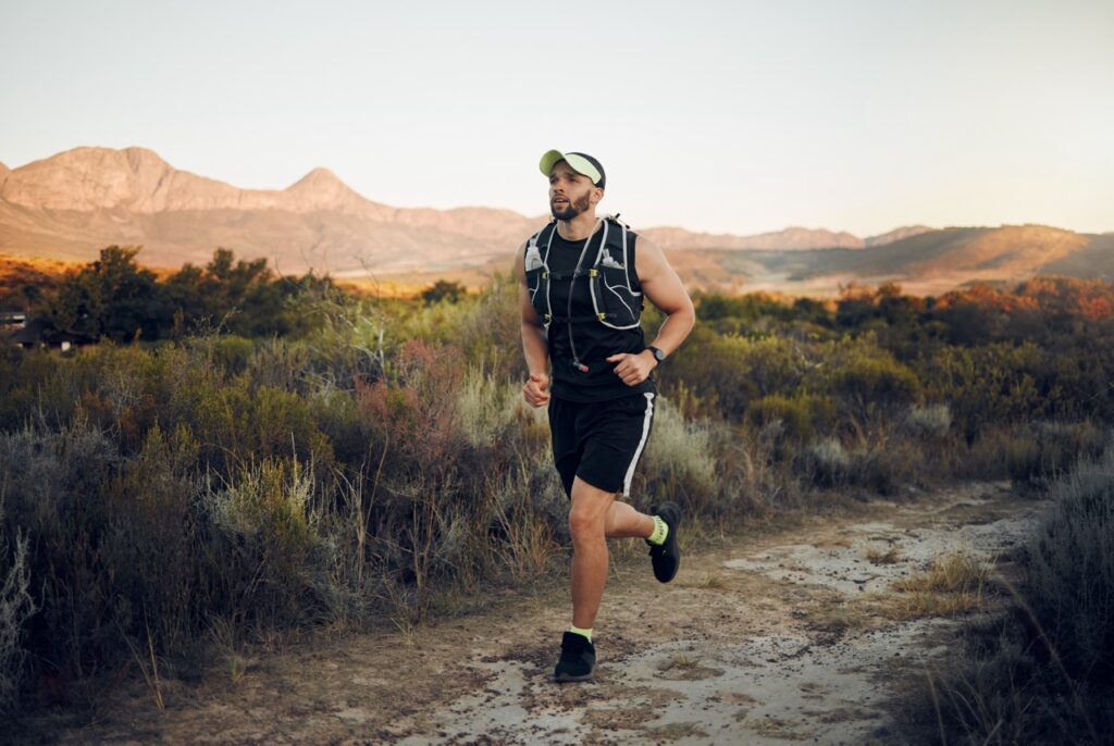 Fitness, training and exercise man running outdoor for a workout. Ambitious latino athlete run and exercising for a marathon. Male runner on nature trails jog to increase cardio health and wellness.