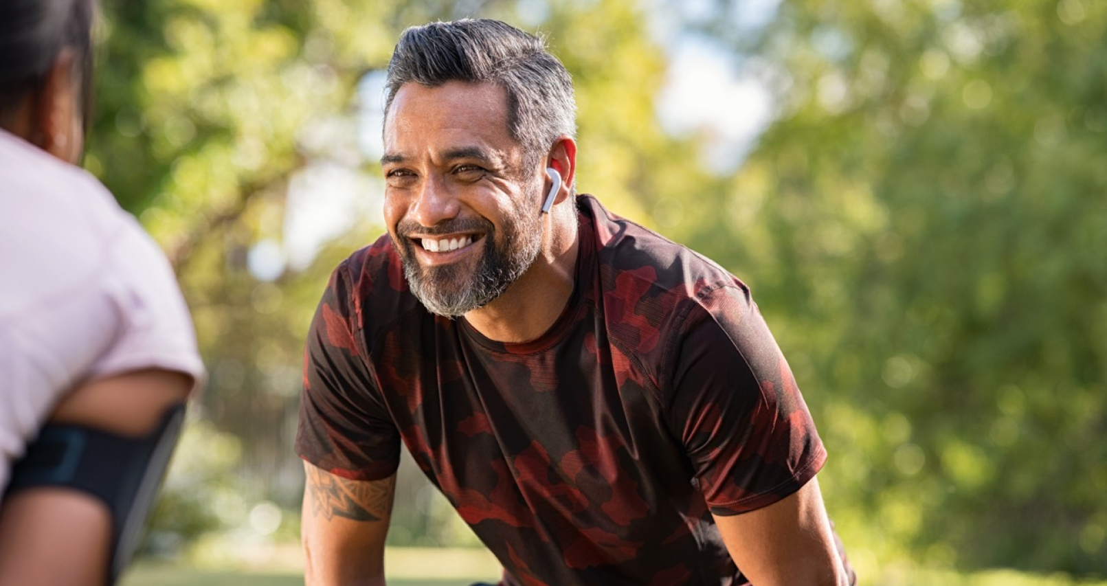 man with beard smiling while standing in front of another person bending over