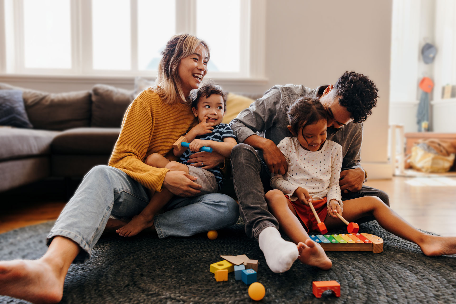 2 adults and 2 children playing with toys on the living room floor