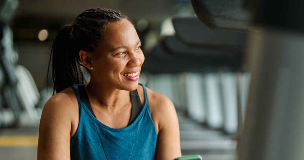 woman at the gym holding phone smiling