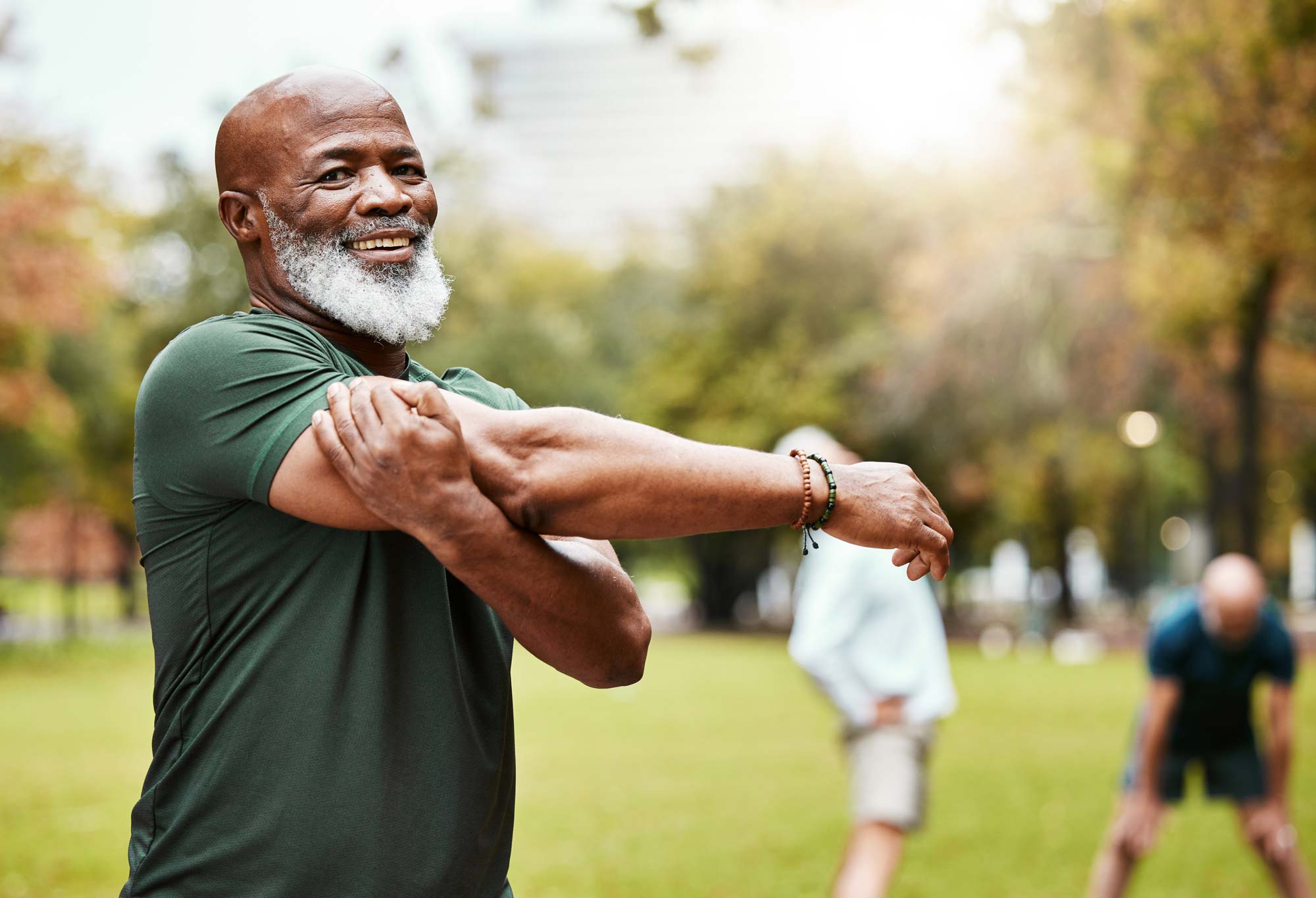 Older man in park stretching his shoulder and arm