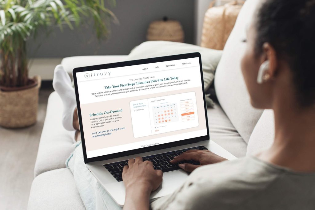 a person sitting with a laptop on their lap looking at the Vitruvy scheduling page