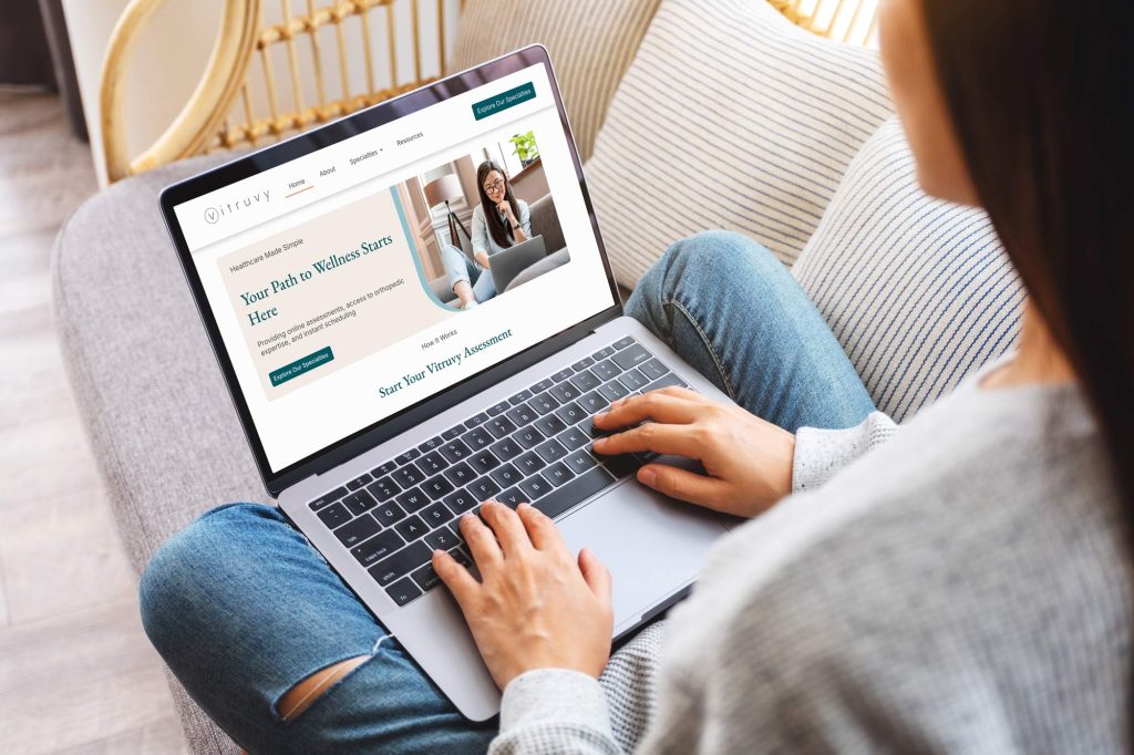 a person sitting with a laptop on their lap looking at the Vitruvy website homepage